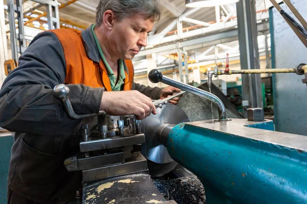 Turner werknemer beheert het proces van de metaalbewerking van mechanische snijden op een draaibank. — Stockfoto