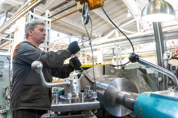 Dreher steuert den metallverarbeitenden Prozess des mechanischen Schneidens auf einer Drehbank. Stockbild