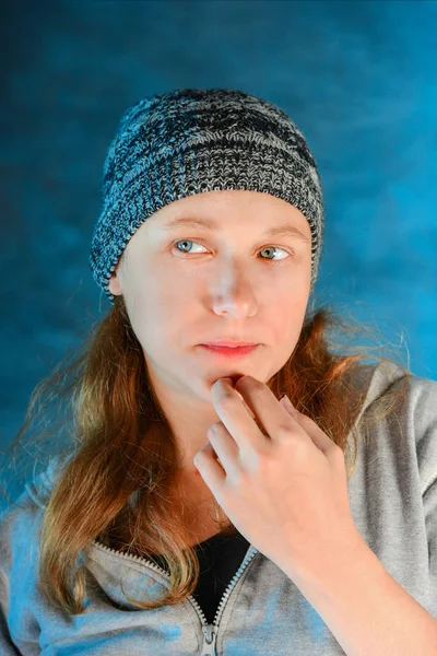 Retrato de uma jovem em um chapéu de malha sem maquiagem, close-up em um fundo azul. A beleza natural de uma mulher . — Fotografia de Stock