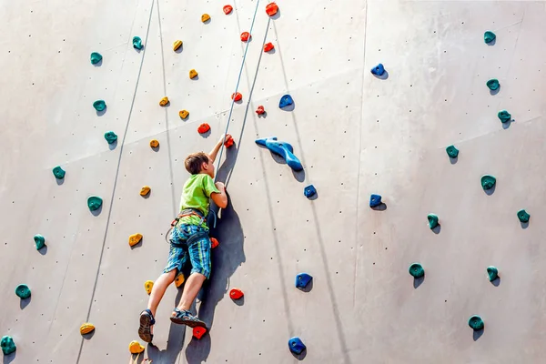 The boy climber climbs on an artificial tower, overcoming obstacles on his way up. — Stock Photo, Image
