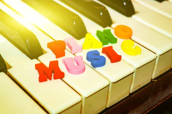 The inscription on the keys of the piano in multi-colored letters, piano music. — Stock Photo, Image