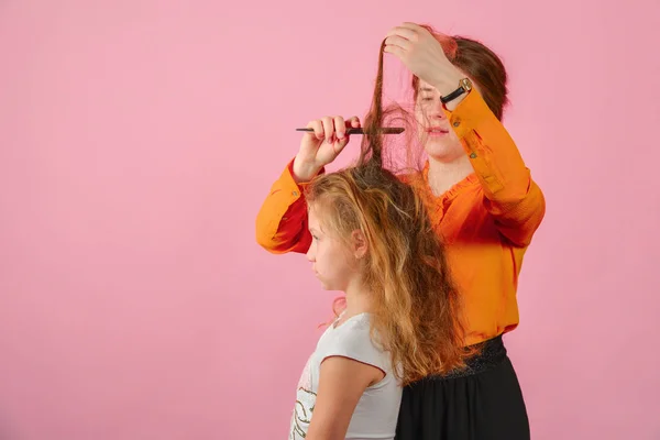 Jeune femme faisant fille coiffure, dans le studio sur un fond rose — Photo