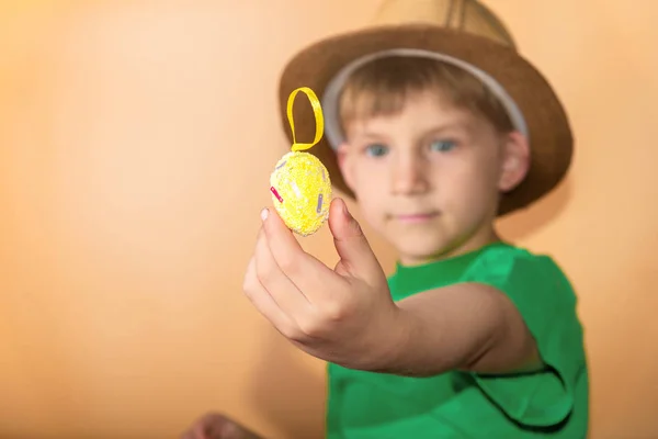 一个戴草帽的男孩手里拿着彩绘的复活节彩蛋. — 图库照片