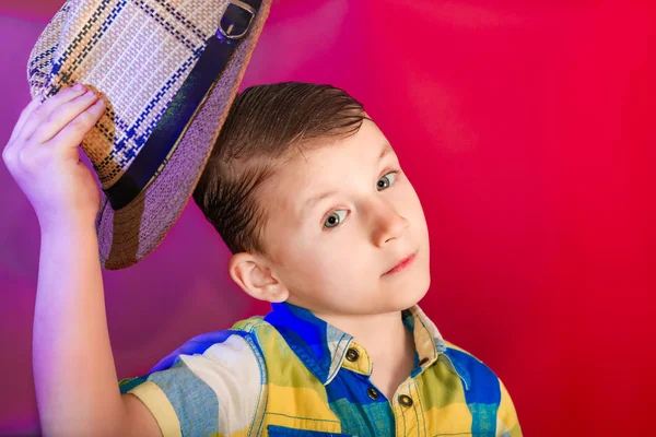 O menino levanta um chapéu de palha sobre a cabeça em um sinal de saudação e simpatia — Fotografia de Stock