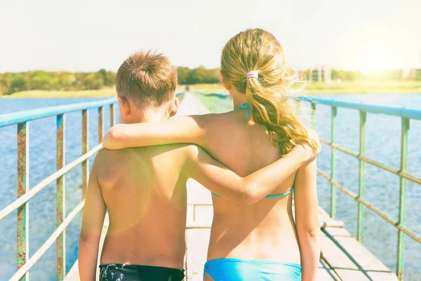 Hermano y hermana de pie en un abrazo en el verano en el puente hacia el mar . —  Fotos de Stock
