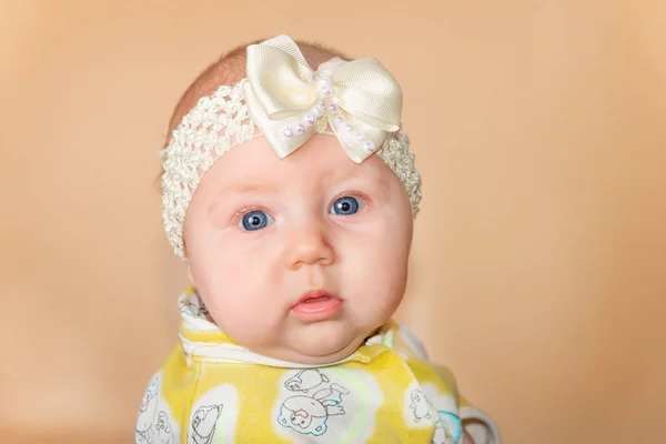 Portrait of a newborn baby in a white bandage with blue eyes on a beige background. — Stock Photo, Image