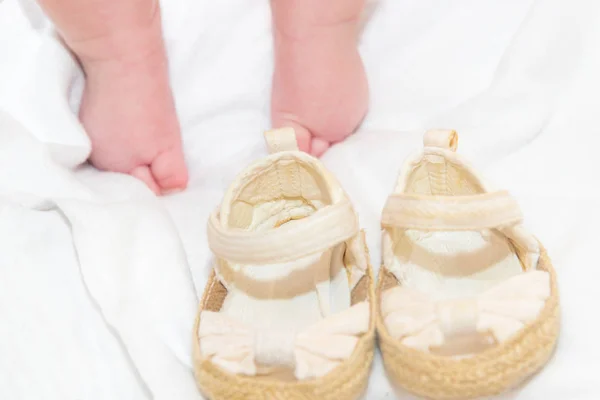 Shoes for a newborn baby, baby booties on the background of small legs. — Stock Photo, Image