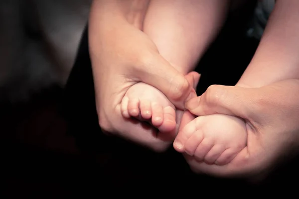 Mutter hält die Füße ihres Neugeborenen in den Händen. — Stockfoto