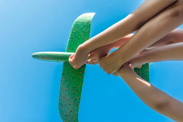 Kinderen houden het vliegtuig met hun handen tegen de blauwe hemel — Stockfoto