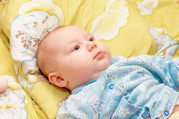 Neugeborenes liegt im Babybett auf gelbem Grund und lächelt in Großaufnahme. — Stockfoto