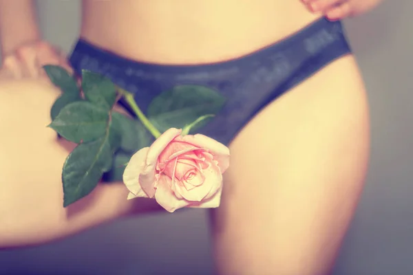 Gadis seksi dengan celana dalam biru memegang mawar di antara kakinya, menyebabkan godaan dan godaan . — Stok Foto