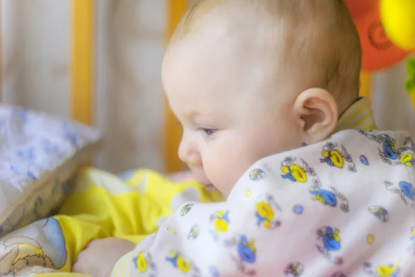 Ein neugeborenes Baby liegt in einem Kinderbett und spielt mit Spielzeug, Nahaufnahme. — Stockfoto