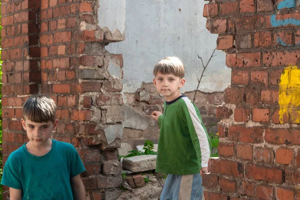 Niños en una casa abandonada, dos niños pobres abandonados, huérfanos como resultado de desastres naturales y acciones militares. Presentación de la foto . — Foto de Stock