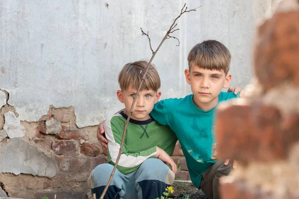 Dos hermanos son huérfanos, escondidos en una casa abandonada, asustados por el desastre y las hostilidades. Presentación de la foto. —  Fotos de Stock