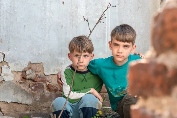 Dos hermanos son huérfanos, escondidos en una casa abandonada, asustados por el desastre y las hostilidades. Presentación de la foto. —  Fotos de Stock