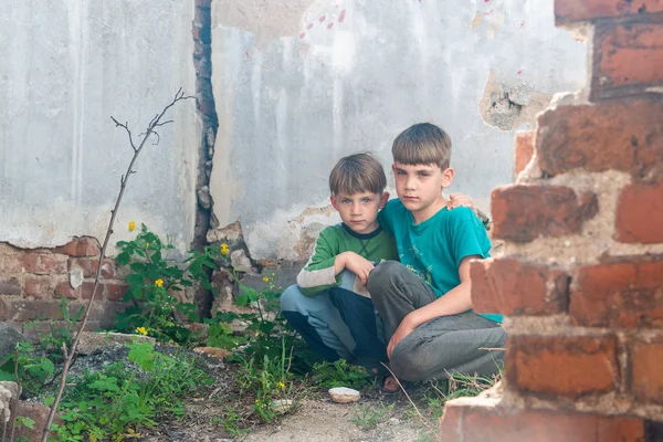 Niños en una casa abandonada, dos niños pobres abandonados, huérfanos como resultado de desastres naturales y acciones militares. Presentación de la foto . —  Fotos de Stock