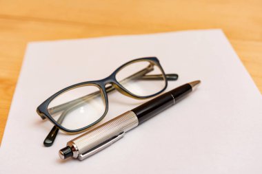 Gözlük ve kalem kayıt için temiz ve beyaz bir kağıda yalan.