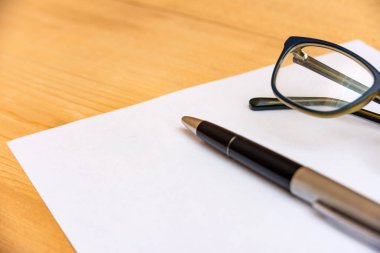 Gözlük ve kalem kayıt için temiz ve beyaz bir kağıda yalan.