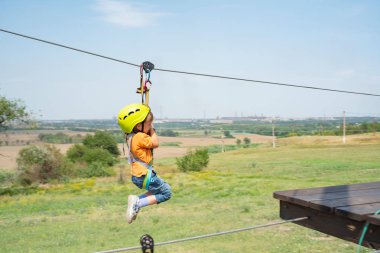 A boy dressed in a protective helmet and insurance, goes down the rope, descends holding a protective cable. clipart