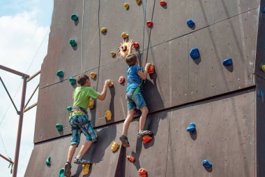 İki küçük dağcılar bir spor lunapark içinde yapay bir dağın zirvesini fethetmek.