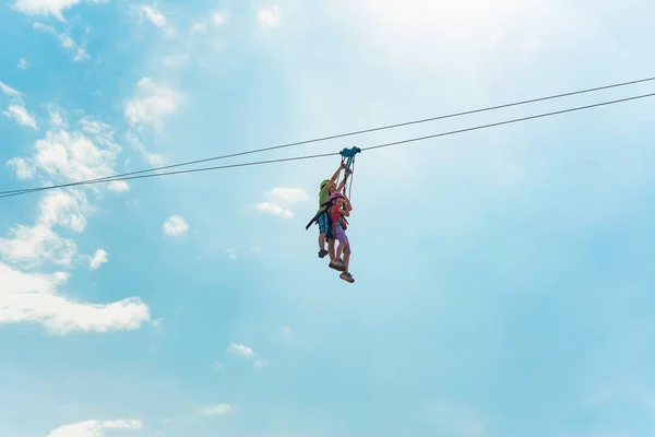 Brother and sister go down the rope in an extreme park. People with the block hold on to the rope and roll down.