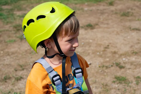一个孩子在一个极端的公园里乘坐缆车。一名身穿防护头盔和保险的男孩克服了缆车上的障碍. — 图库照片
