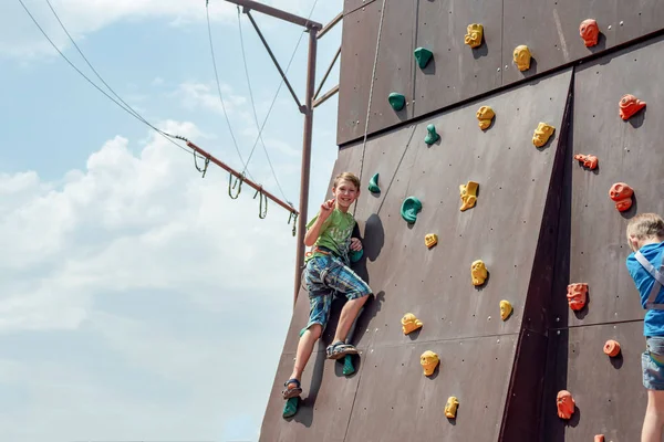 Wspinaczka skalna na sztucznym wzroście. Chłopiec wspina się na ścianie w ekstremalnym parku. — Zdjęcie stockowe