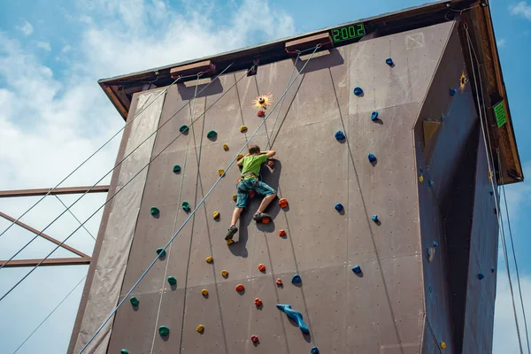 Wspinaczka skalna na sztucznym wzroście. Chłopiec wspina się na ścianie w ekstremalnym parku. — Zdjęcie stockowe