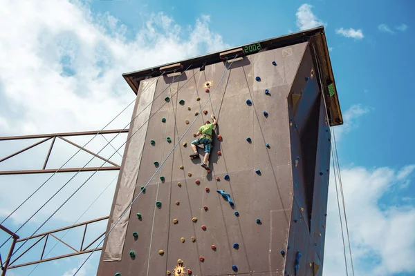 Rock climbing on an artificial rise. The boy climbs on the wall in an extreme park. — Stock Photo, Image