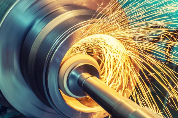 Silindirik bir parçanın iç gıcırtısı ve makinede aşındırıcı bir tekerlek var. Kıvılcımlar farklı yönlere uçuyor. Metal işleme.