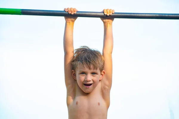 一个小男孩挂在水平杆上，什么也做不了. — 图库照片