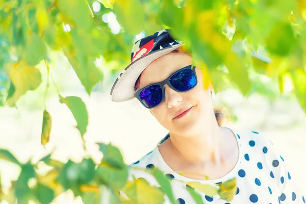 안경과 모자를 쓴 소녀의 초상화, 공원에서 선글라스를 착용한 젊고 아름다운 소녀. — 스톡 사진