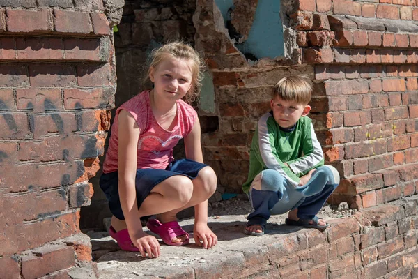 Fratello e sorella sono stati lasciati soli a causa di conflitti militari e disastri naturali. Bambini in una casa in rovina e abbandonata. Foto in scena . — Foto Stock