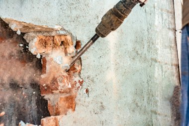 Bir elektrikli jakhammer ile duvar ve açıklıkların sökme, yakın çekim, keski altından toz boğuk.