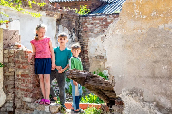 Pobres huérfanos en el contexto de edificios destruidos, el concepto de la vida de los niños de la calle. Foto escenificada. —  Fotos de Stock