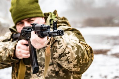 Akm silahlı bir asker, düşmanı hedef alıyor. Namlu ve namlu makinesi yakın.