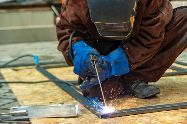 İş yerinde bir kaynakçı şekilli boru metal bir yapı birleştirir.