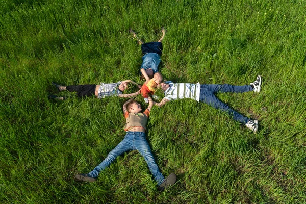 Çim üzerinde yatan çocuklar, mutlu ve neşeli kardeşler, üst görünüm — Stok fotoğraf