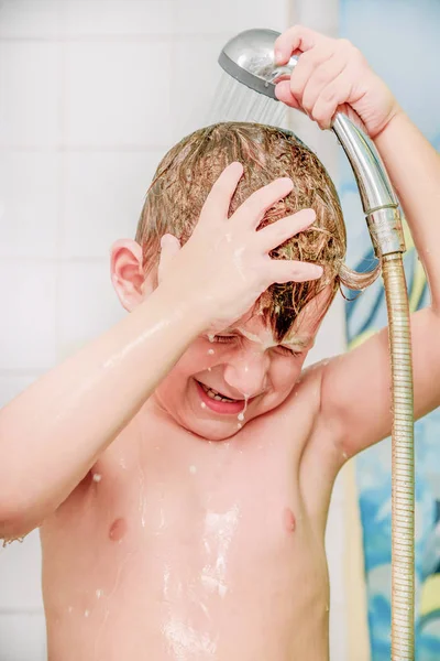 Маленький мальчик купается в ванной и смывает волосы с шампуня под душем . — стоковое фото