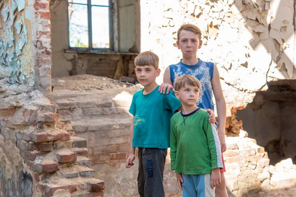 Niños en un edificio abandonado y destruido en la zona de conflictos militares y militares. El concepto de problemas sociales de los niños sin hogar. Foto escenificada . —  Fotos de Stock