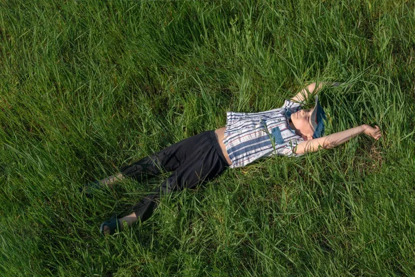 Un niño feliz y alegre yace en la hierba, una infancia despreocupada . — Foto de Stock