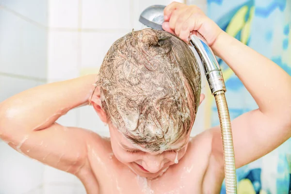 A little boy bathes in the bathroom and washes away the hair from the shampoo under the shower. — Stock Photo, Image