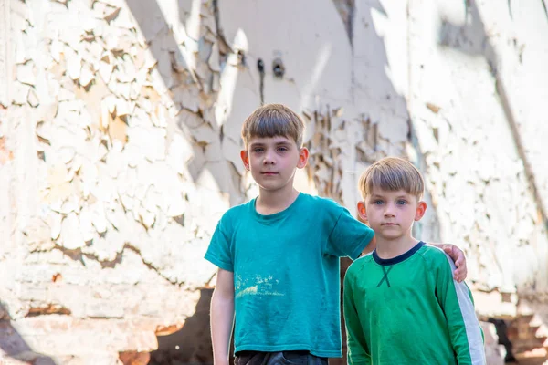 Niños en un edificio abandonado y destruido en la zona de conflictos militares y militares. El concepto de problemas sociales de los niños sin hogar. Foto escenificada . —  Fotos de Stock
