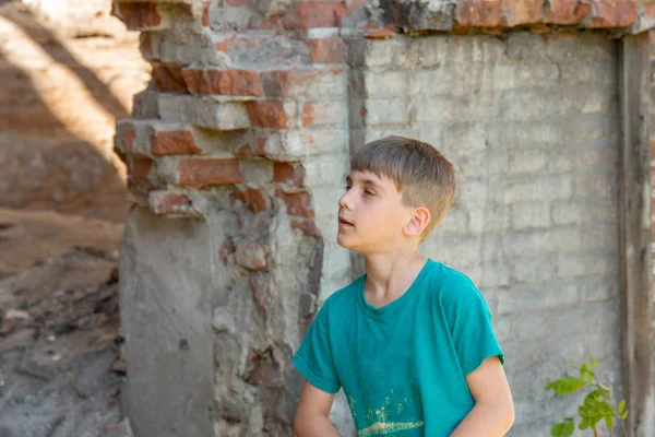 Niños en un edificio abandonado y destruido en la zona de conflictos militares y militares. El concepto de problemas sociales de los niños sin hogar. Foto escenificada . —  Fotos de Stock