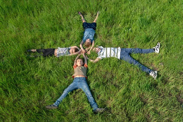 Crianças deitadas na grama, irmãos e irmãs felizes e alegres, vista superior — Fotografia de Stock