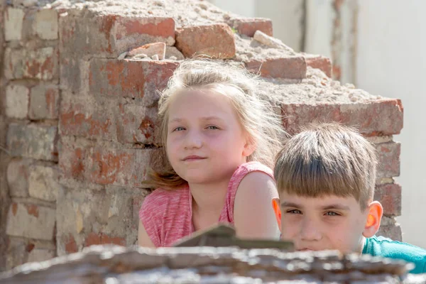 Bambini in un edificio abbandonato e distrutto nella zona dei conflitti militari e militari. Il concetto di problemi sociali dei bambini senzatetto. Foto in scena . — Foto Stock