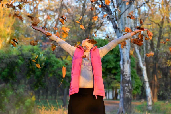 Щаслива і радісна жінка кидає осіннє листя в парку . — стокове фото