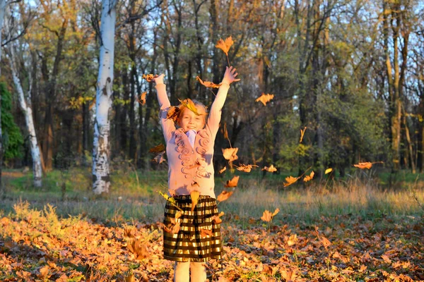 Das Mädchen hat Spaß und wirft Blätter in den Herbstpark. — Stockfoto