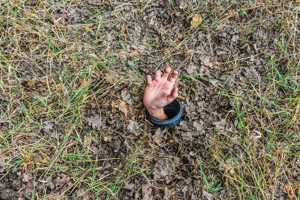The human hand is buried in the ground, asking for help from under the ground... — Stock Photo, Image