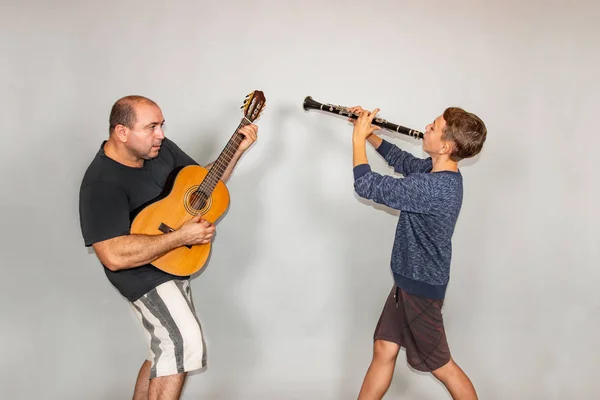 El chico toca la guitarra y el clarinete en diferentes poses, posando en el estudio . —  Fotos de Stock